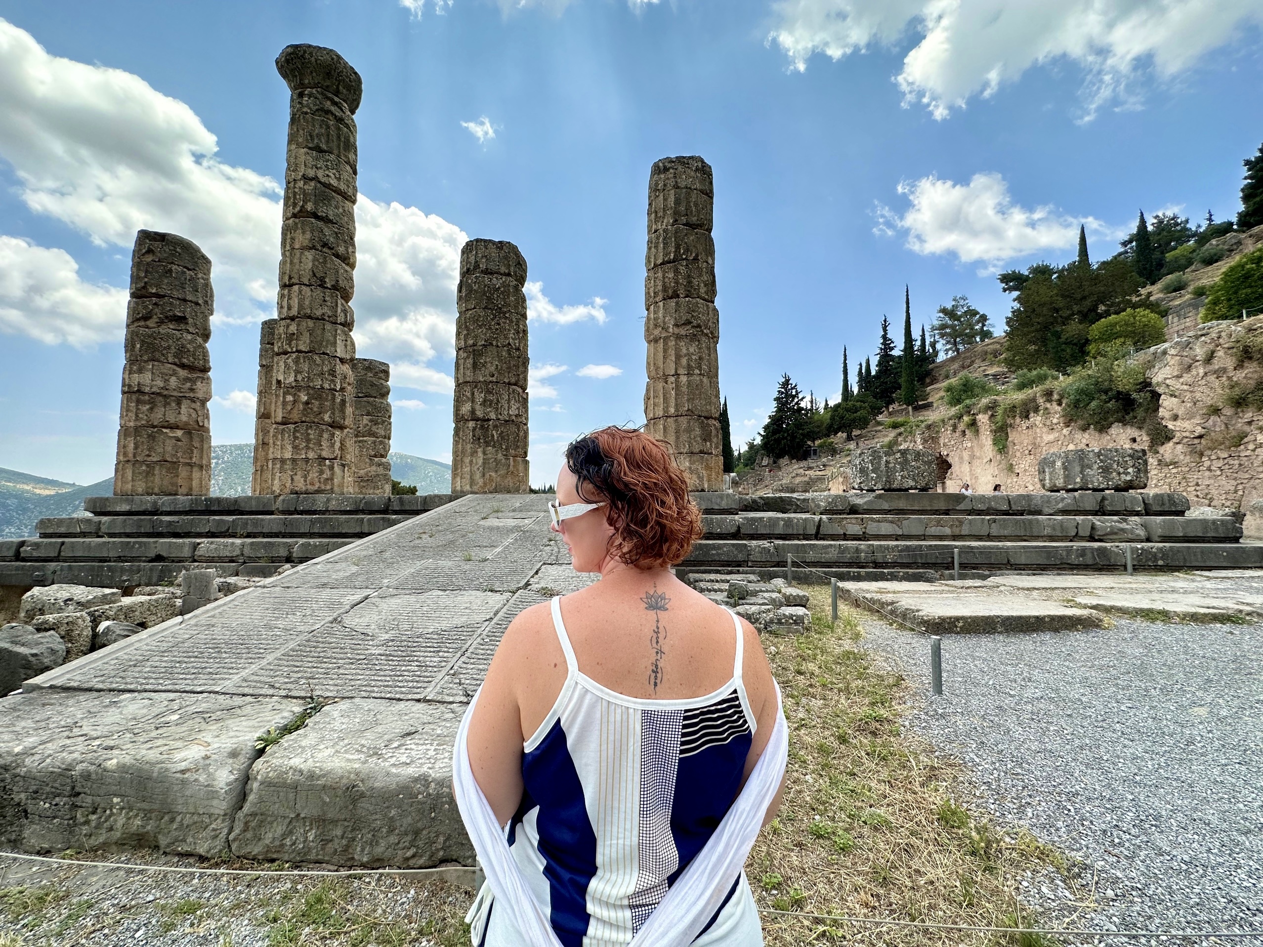 Woman infront of Delphi temple - tattoo is one of the inscriptions from the temple nosce te ipsum